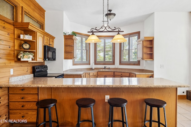 kitchen with a healthy amount of sunlight, black appliances, kitchen peninsula, and a breakfast bar