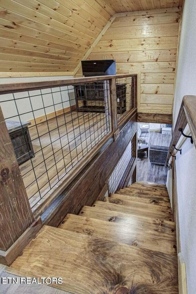 stairway featuring wood ceiling, lofted ceiling, wooden walls, and hardwood / wood-style floors