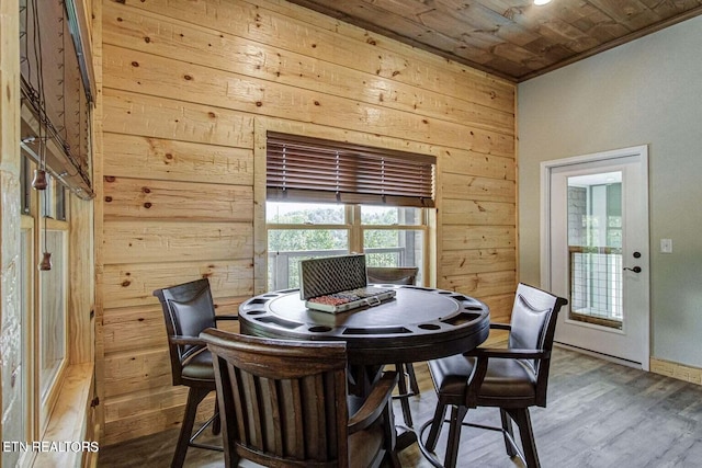 dining room with wooden walls, wooden ceiling, hardwood / wood-style floors, and crown molding