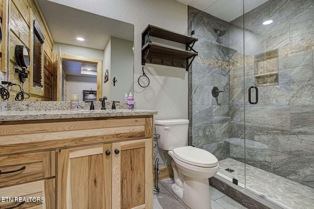 bathroom featuring vanity, toilet, and a shower with door