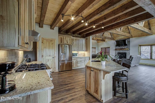kitchen with light stone counters, light brown cabinets, beam ceiling, a center island, and high end refrigerator