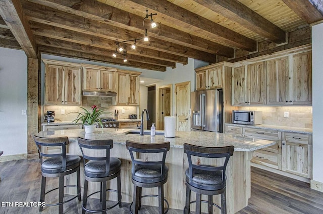 kitchen featuring beam ceiling, sink, a kitchen island with sink, dark wood-type flooring, and stainless steel appliances