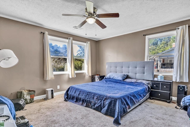 bedroom with ceiling fan, light colored carpet, a textured ceiling, and multiple windows