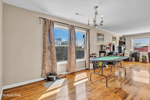 rec room with light hardwood / wood-style floors, a notable chandelier, and ornamental molding