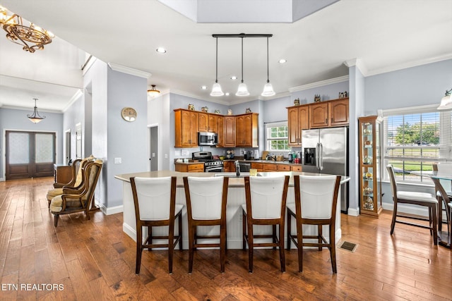 kitchen featuring crown molding, dark hardwood / wood-style floors, an island with sink, and stainless steel appliances