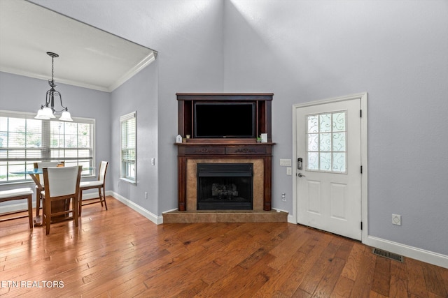 living room with an inviting chandelier, hardwood / wood-style flooring, a fireplace, and crown molding