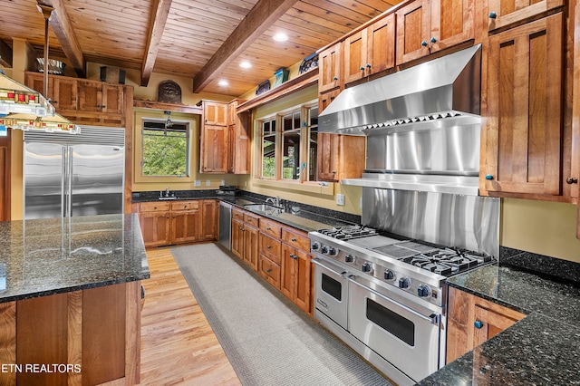 kitchen with dark stone counters, decorative light fixtures, light hardwood / wood-style flooring, and high quality appliances