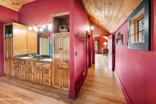 corridor featuring wood ceiling, lofted ceiling, sink, and light hardwood / wood-style flooring