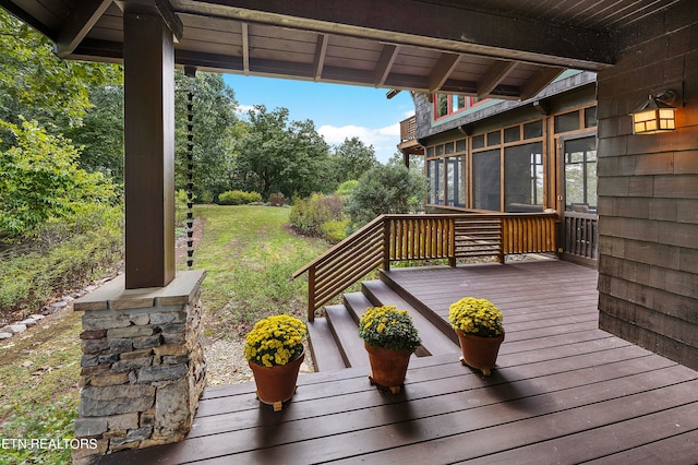 wooden terrace featuring a lawn and a sunroom