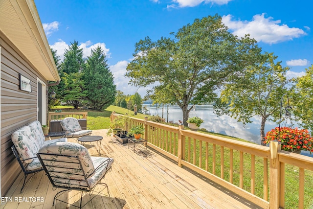 wooden terrace featuring a lawn and a water view