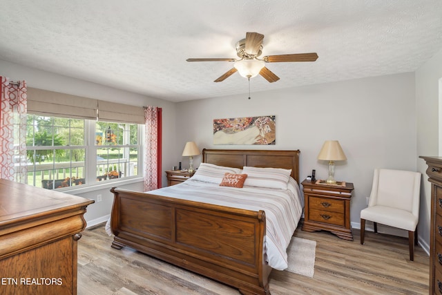 bedroom with ceiling fan, a textured ceiling, and light hardwood / wood-style flooring