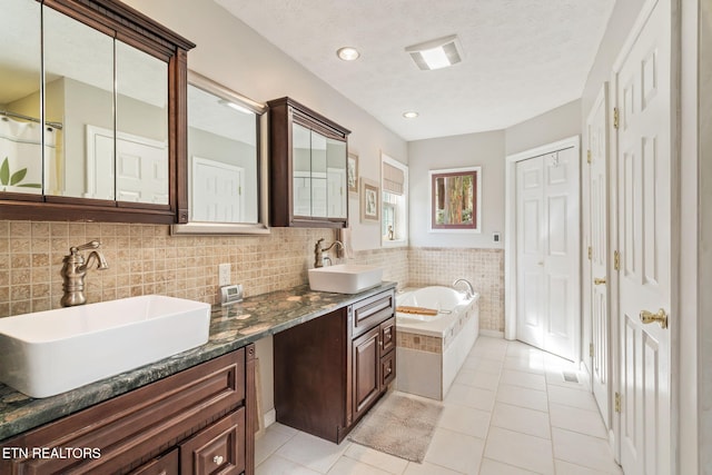 bathroom with vanity, a textured ceiling, tile patterned flooring, and a bath