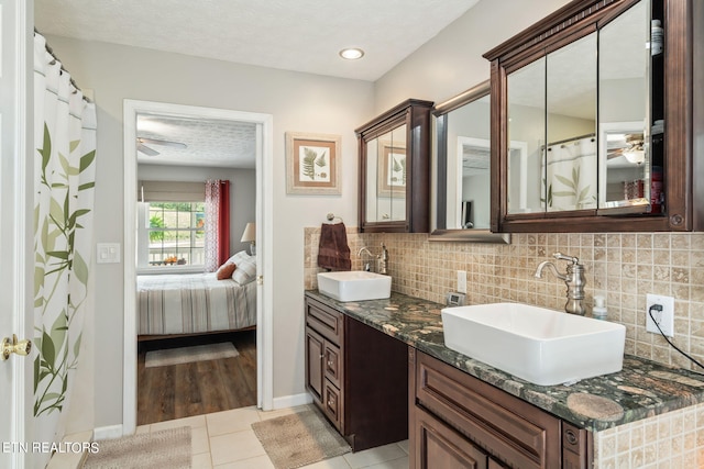 bathroom featuring vanity, backsplash, a textured ceiling, and tile patterned floors