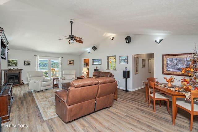 living room featuring ceiling fan, a textured ceiling, light hardwood / wood-style flooring, and vaulted ceiling