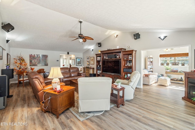 living room with a textured ceiling, wood-type flooring, vaulted ceiling, and ceiling fan