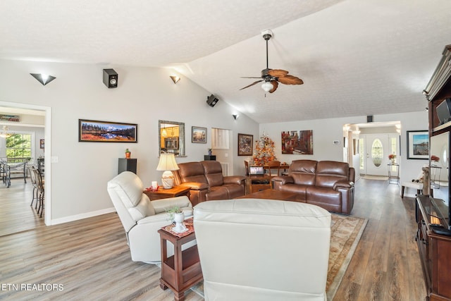 living room with wood-type flooring, lofted ceiling, ceiling fan, and a textured ceiling