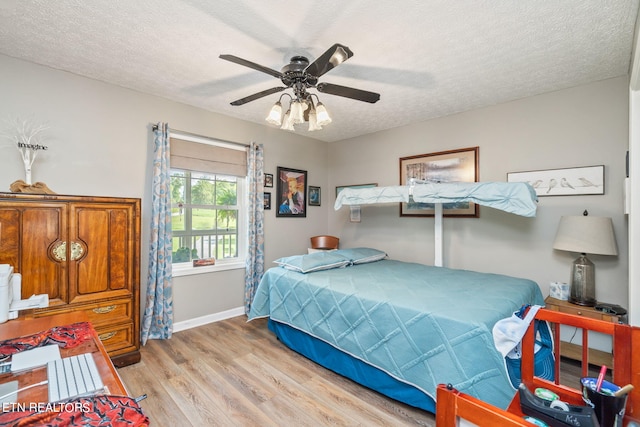 bedroom with a textured ceiling, light hardwood / wood-style floors, and ceiling fan