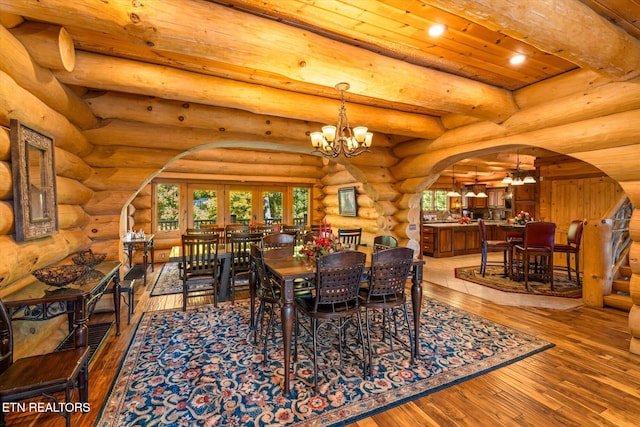 dining room with rustic walls, an inviting chandelier, wood ceiling, and light hardwood / wood-style flooring