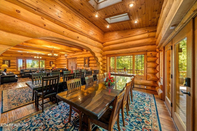 dining area featuring plenty of natural light, vaulted ceiling with skylight, hardwood / wood-style floors, and log walls