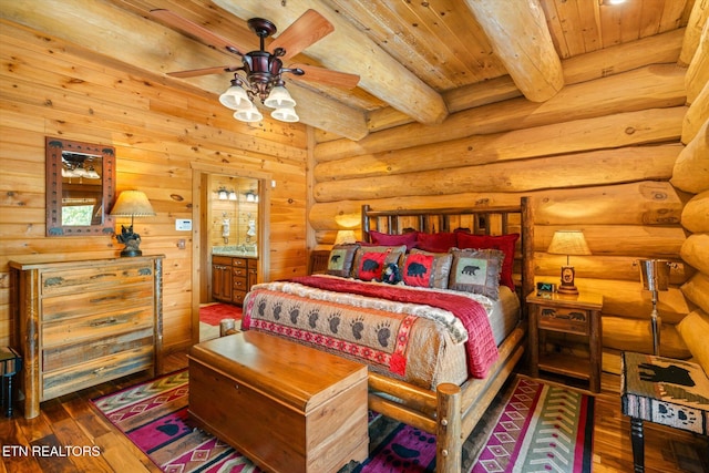 bedroom featuring ensuite bath, beam ceiling, dark hardwood / wood-style flooring, wooden ceiling, and log walls