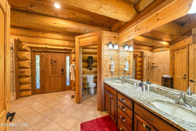 bathroom with beamed ceiling, vanity, toilet, and log walls