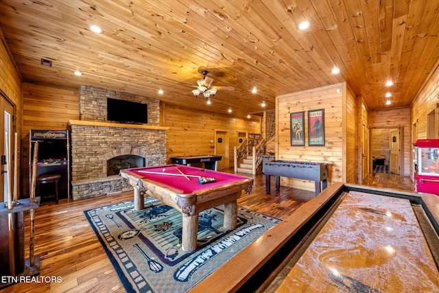 rec room with pool table, a stone fireplace, wood ceiling, hardwood / wood-style floors, and wooden walls