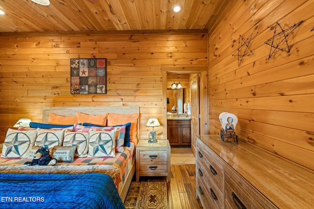 unfurnished bedroom featuring light hardwood / wood-style floors, wooden walls, wood ceiling, and connected bathroom