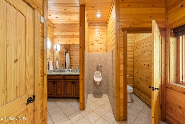 bathroom featuring vanity, tile patterned flooring, wooden walls, and toilet