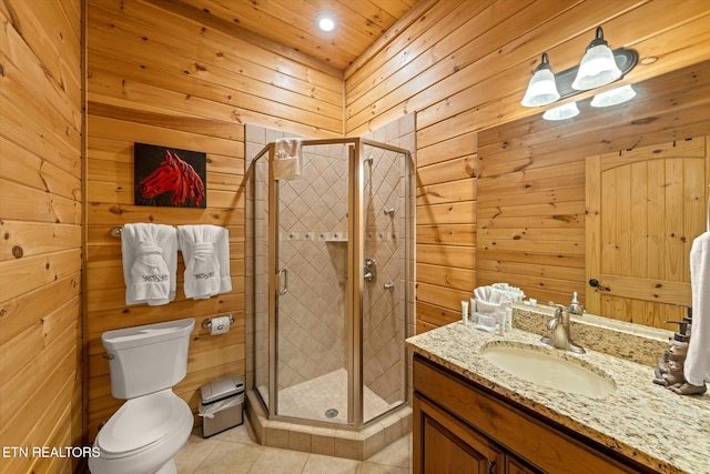 bathroom with tile patterned floors, vanity, wood walls, an enclosed shower, and toilet