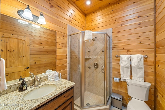 bathroom featuring vanity, a shower with shower door, wooden walls, and toilet