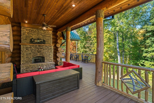 wooden terrace with ceiling fan and an outdoor living space with a fireplace