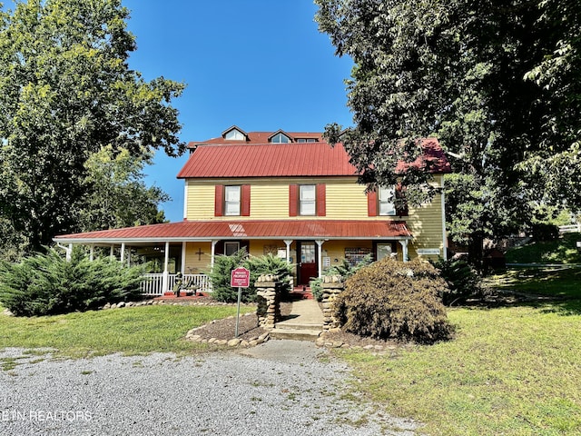 country-style home with metal roof, a front lawn, and covered porch