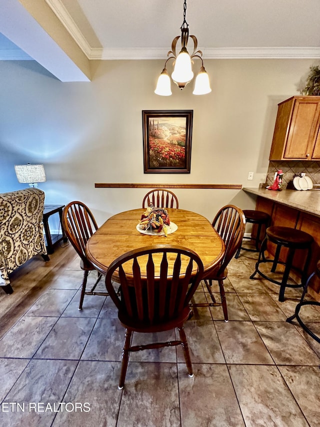 dining space with an inviting chandelier, ornamental molding, and tile patterned flooring