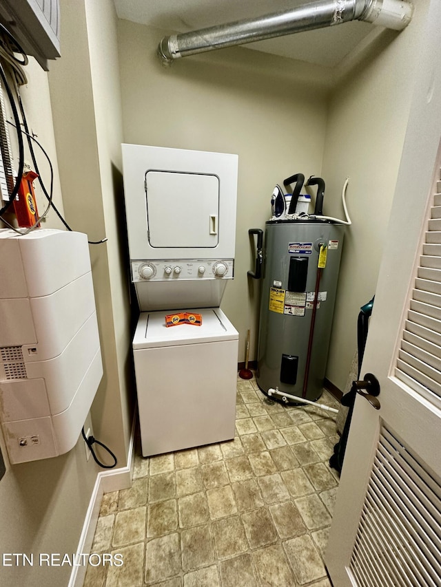 laundry area featuring stacked washer and clothes dryer, electric water heater, laundry area, and baseboards
