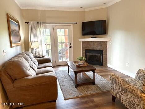 living room with wood finished floors, a tile fireplace, and ornamental molding