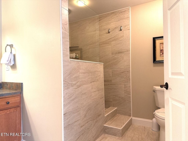 bathroom featuring toilet, a walk in shower, vanity, and baseboards