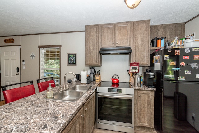 kitchen featuring sink, black refrigerator, ornamental molding, a kitchen bar, and stainless steel range with electric cooktop