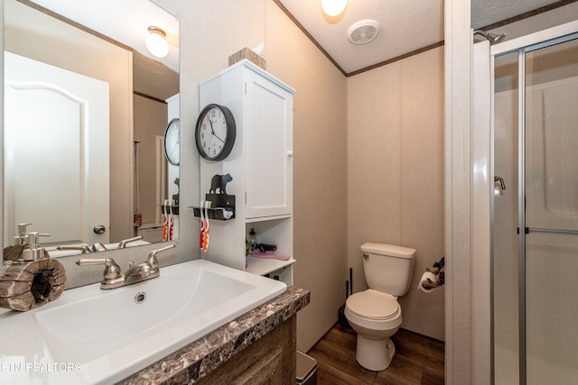 bathroom with toilet, hardwood / wood-style floors, a shower with door, vanity, and a textured ceiling