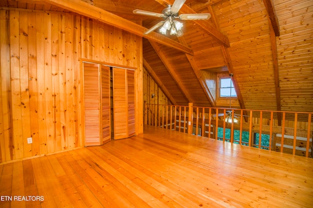 additional living space with wood walls, wooden ceiling, lofted ceiling with beams, and hardwood / wood-style flooring