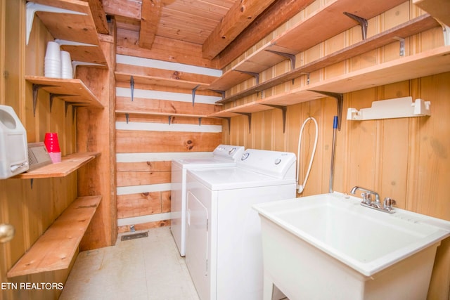 clothes washing area featuring sink, wooden walls, independent washer and dryer, and wood ceiling