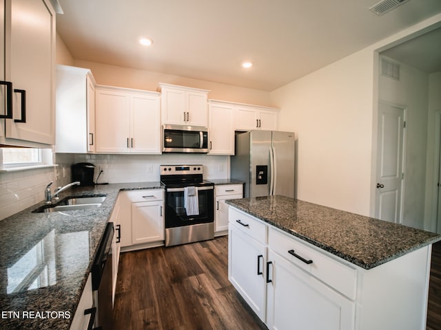 kitchen with stainless steel appliances, white cabinets, dark wood-type flooring, sink, and dark stone counters