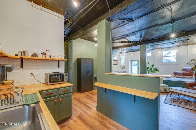 kitchen with light wood-type flooring, backsplash, and wooden counters