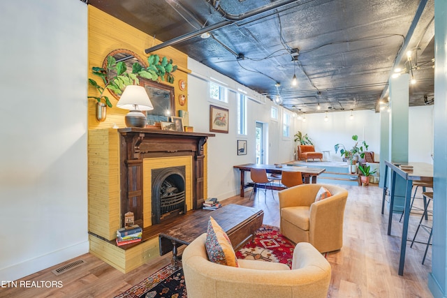 living room featuring rail lighting, wooden walls, and hardwood / wood-style flooring