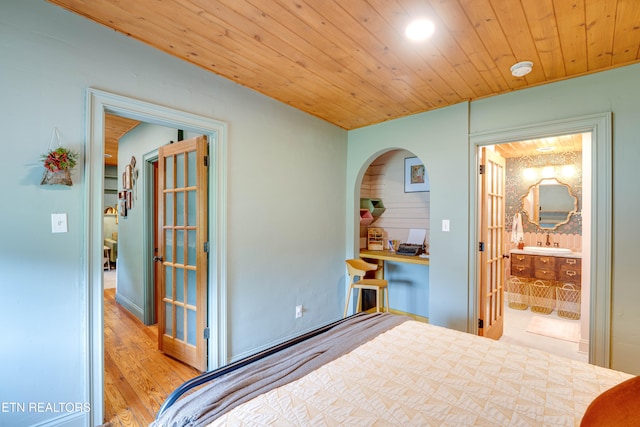 bedroom with light hardwood / wood-style flooring, connected bathroom, and wood ceiling