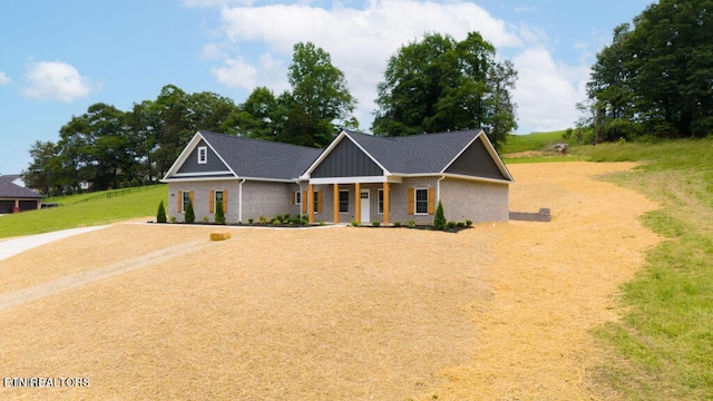 view of front of property with a porch, brick siding, board and batten siding, and a front lawn