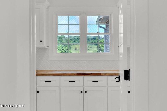 interior space with butcher block counters, white cabinets, and tasteful backsplash