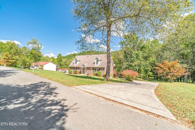 cape cod house featuring a front yard and a garage