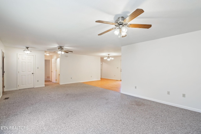 carpeted empty room with ceiling fan with notable chandelier