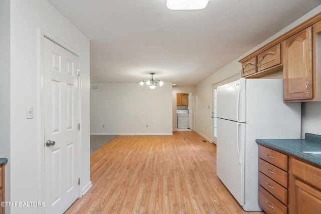 kitchen with an inviting chandelier, washer / dryer, white refrigerator, and light hardwood / wood-style floors