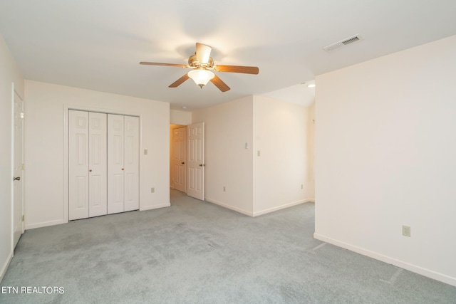 unfurnished bedroom featuring ceiling fan, a closet, and light colored carpet